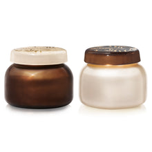 Two glass scented candle jars with lids on a white background