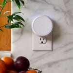 Smart plug device on a marble surface with fruits and a plant in the foreground