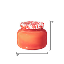 Red glass jar with floral lid on a white background