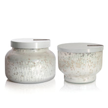 Two glass scented candle jars with silver lids on a white background