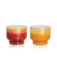 Two glass scented candle containers with gold lids on a white background