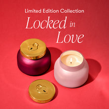 Pink candle with gold lid on a red background, featuring 'Locked in Love' collection text.