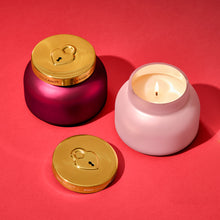 Pink candle with gold lid and pink container on a red background