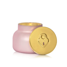 Pink candle with a gold lid featuring a lock design on a white background