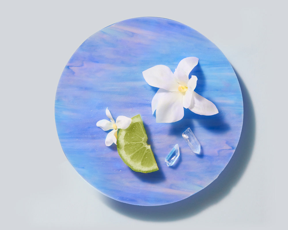 A flower and slice of lime on a blue glass plate