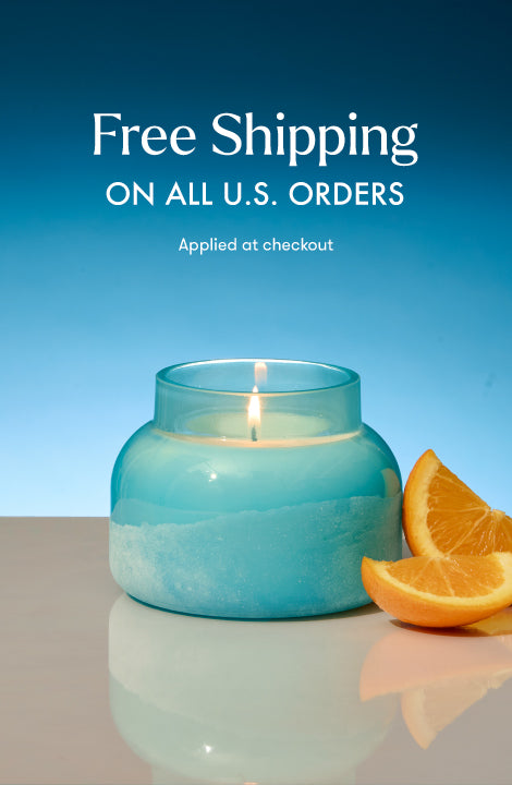 Candle lit on a marble surface with orange slices next to it