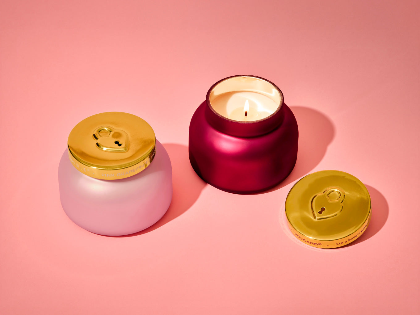Candle in a pink holder with gold lid on a pink background