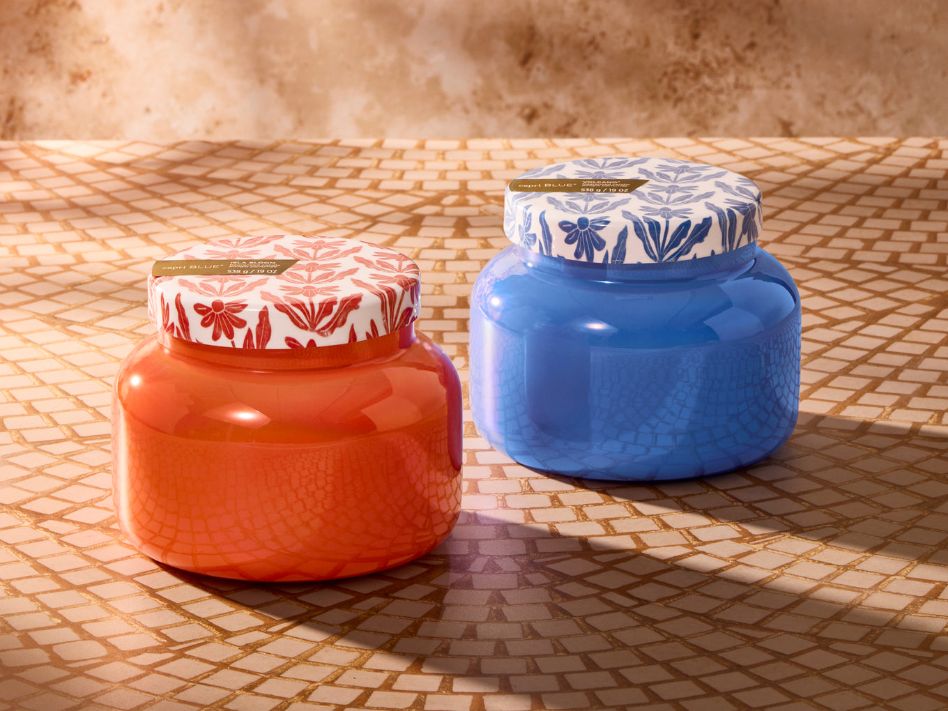Two colorful jars with decorative lids on a textured surface