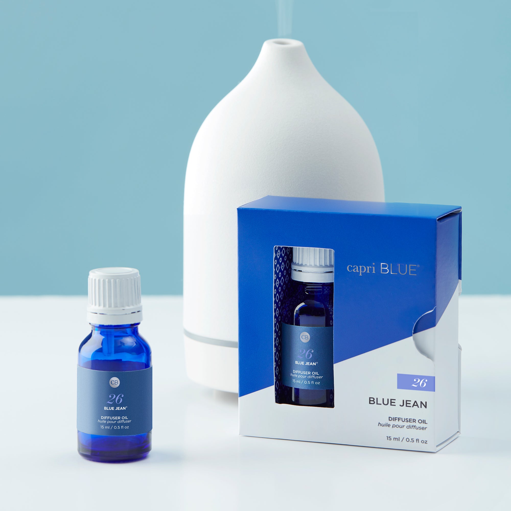 Capri Blue Blue Jean diffuser oil bottle and packaging on a light blue background