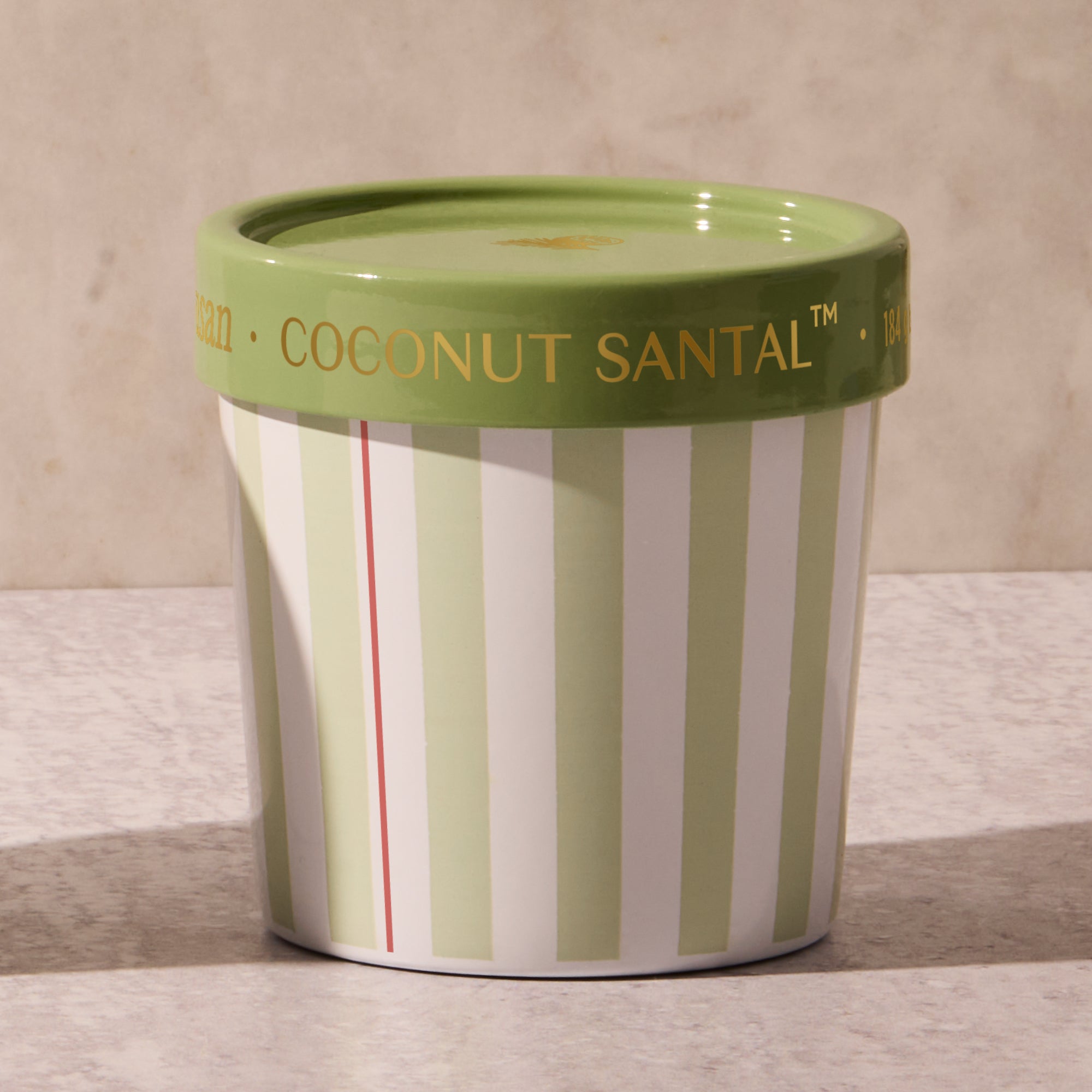 Green and white striped container with a green lid on a marble surface