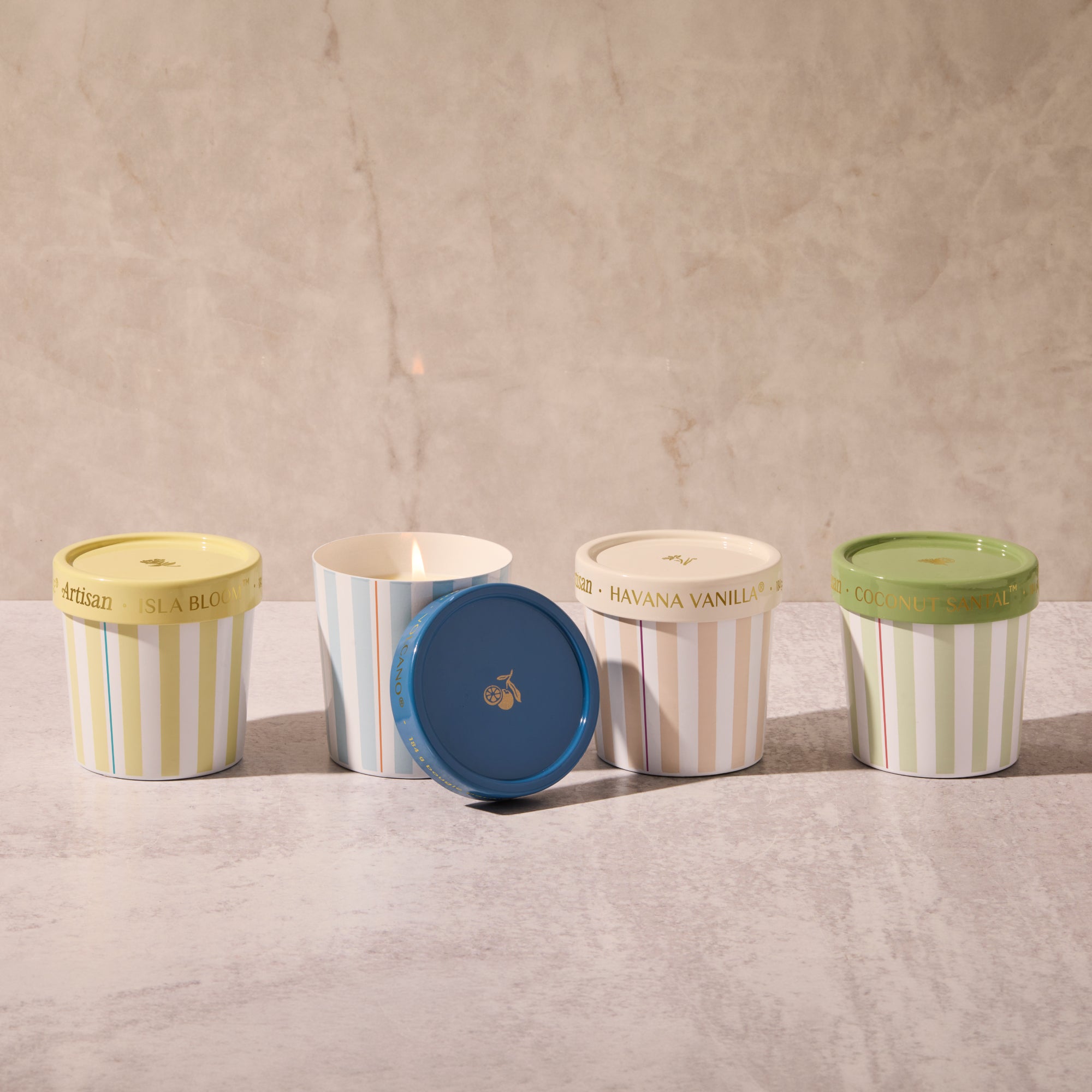Five ice cream containers with striped patterns and colorful lids on a textured surface.