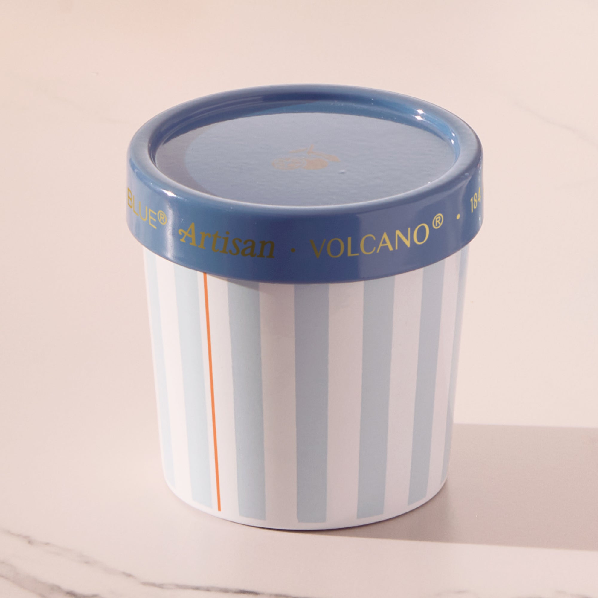 Cylindrical container with striped design and blue lid on a light background