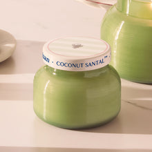 Green candle jar with 'Coconut Santal' label on a white surface