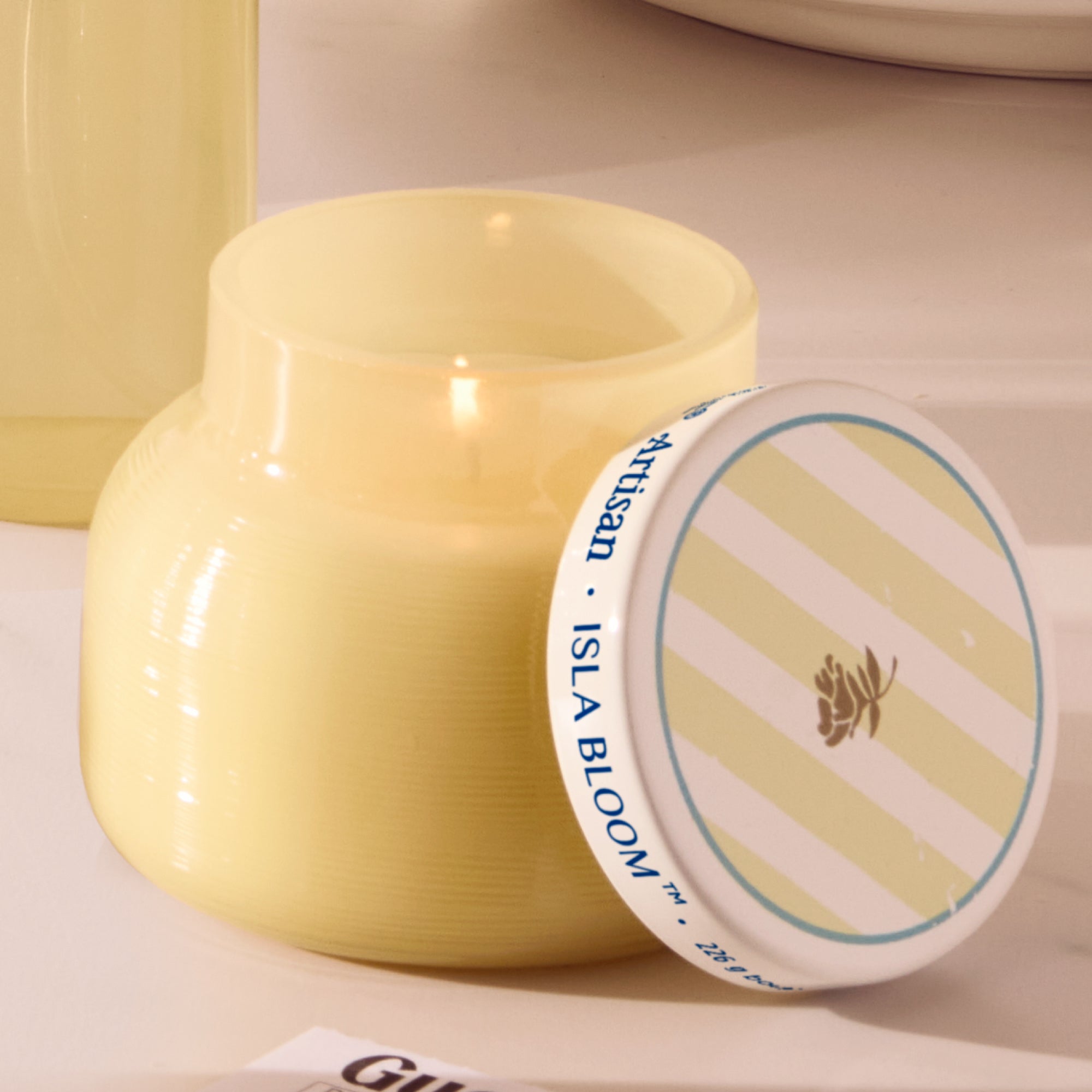 Yellow ceramic jar with a striped label on a beige background