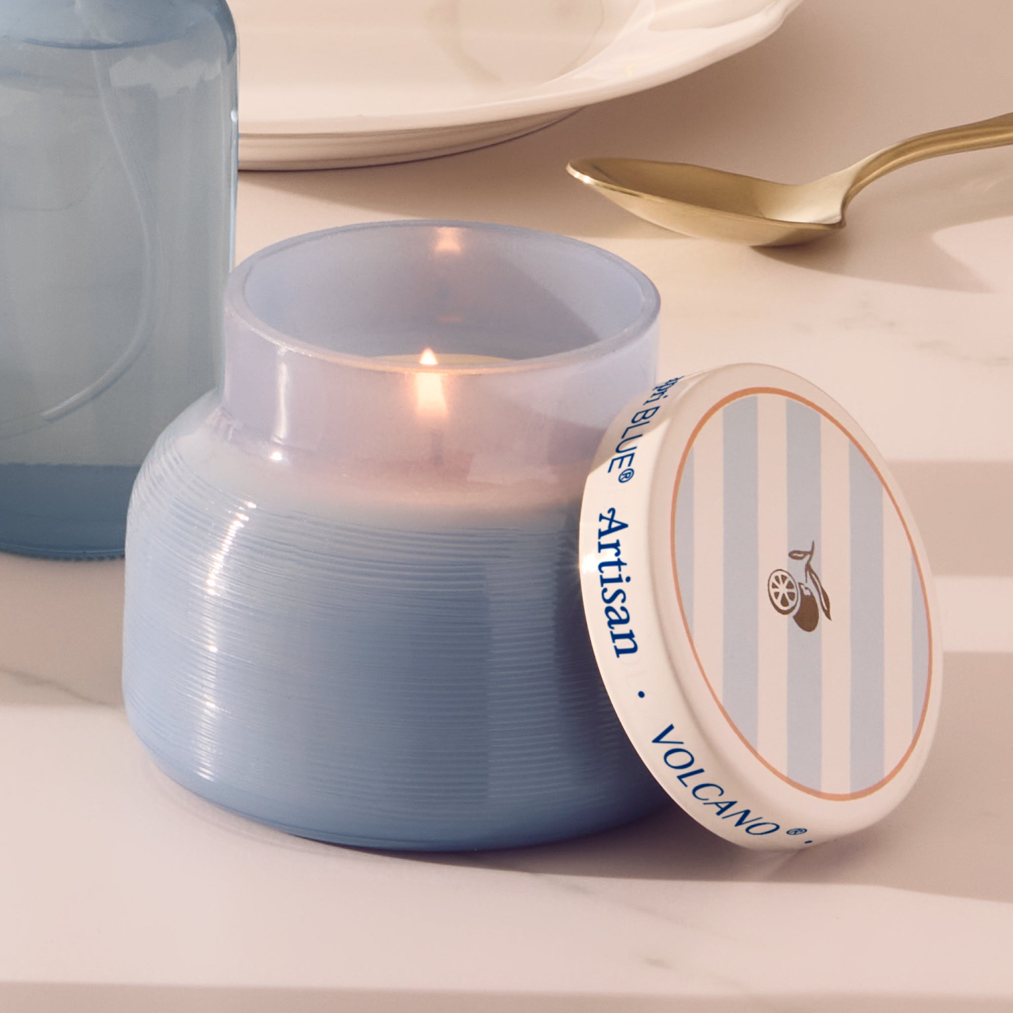 Blue candle with 'Artisan Volcano' label on a white surface