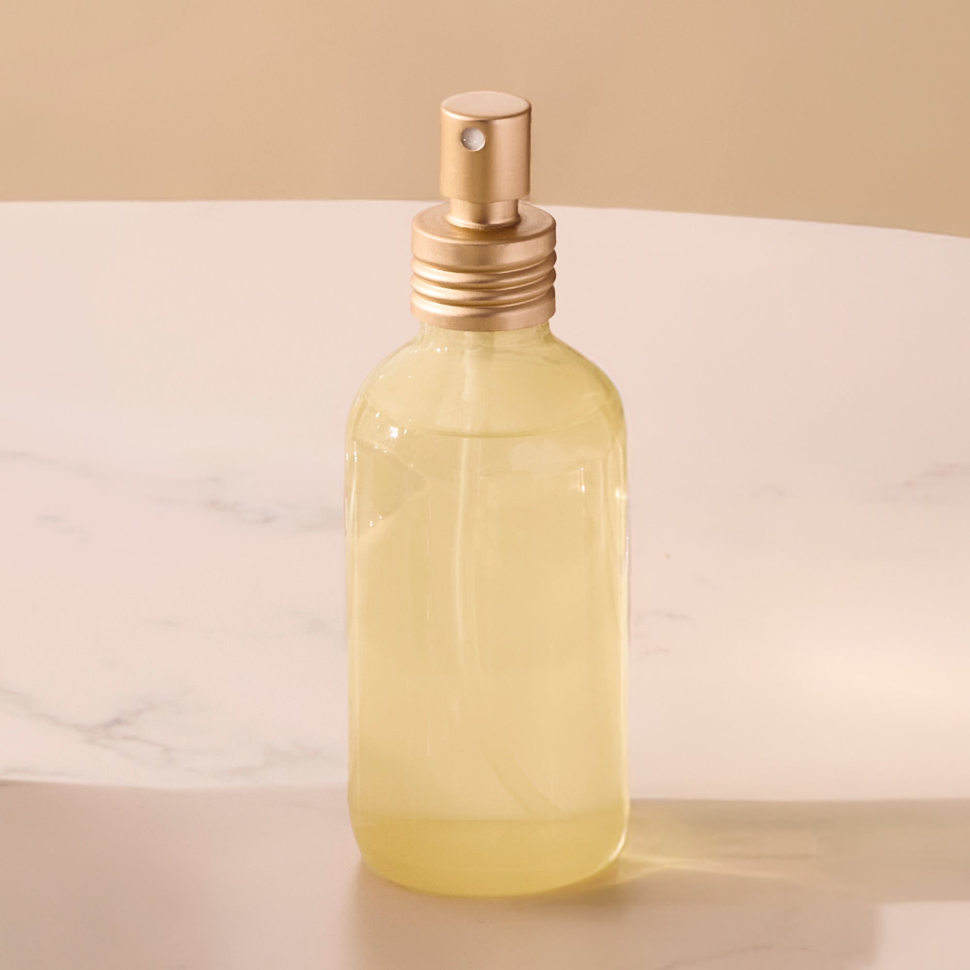 Clear glass bottle with gold cap on a beige background