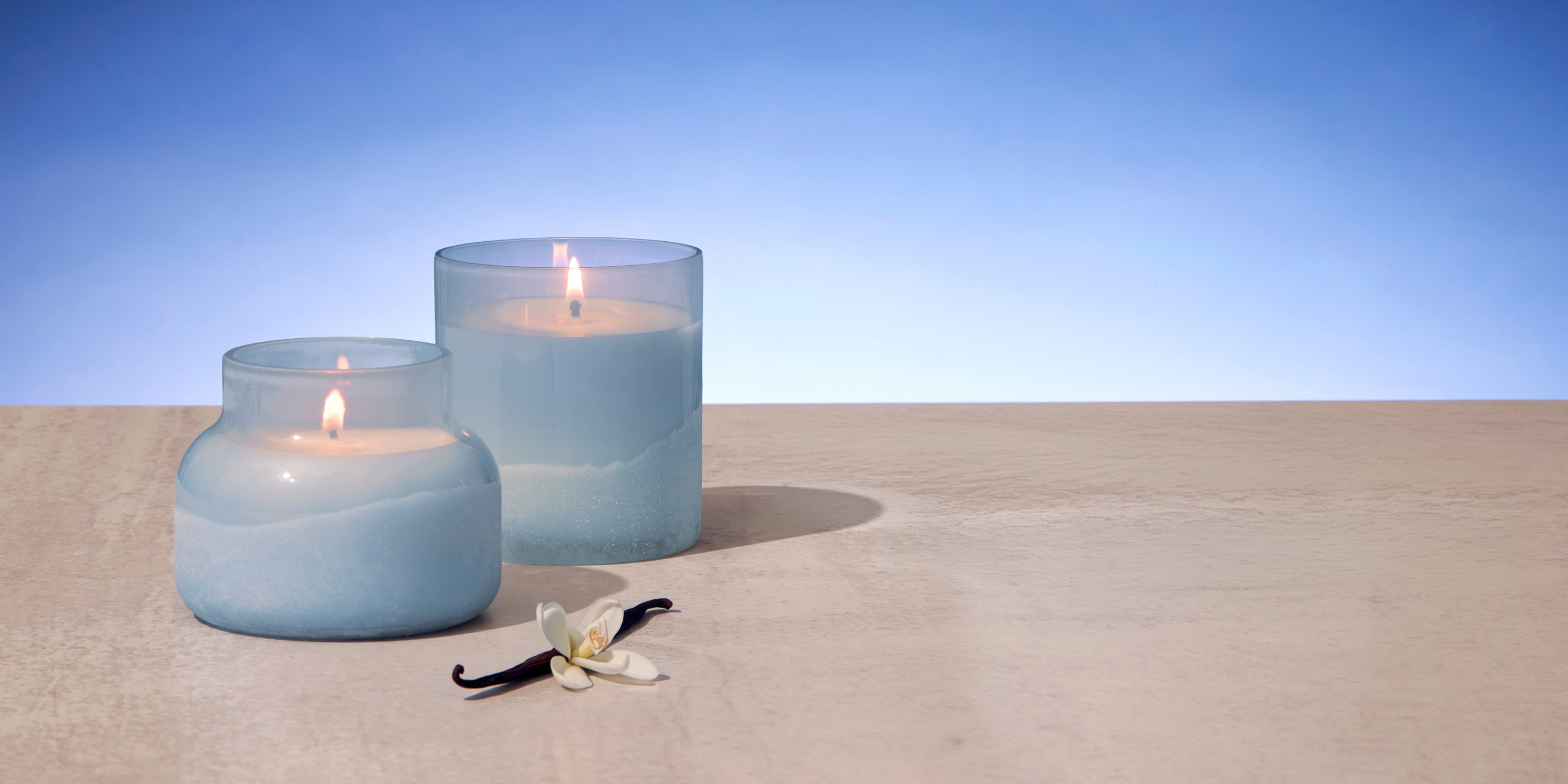 Two blue candles on sand with a clear blue sky