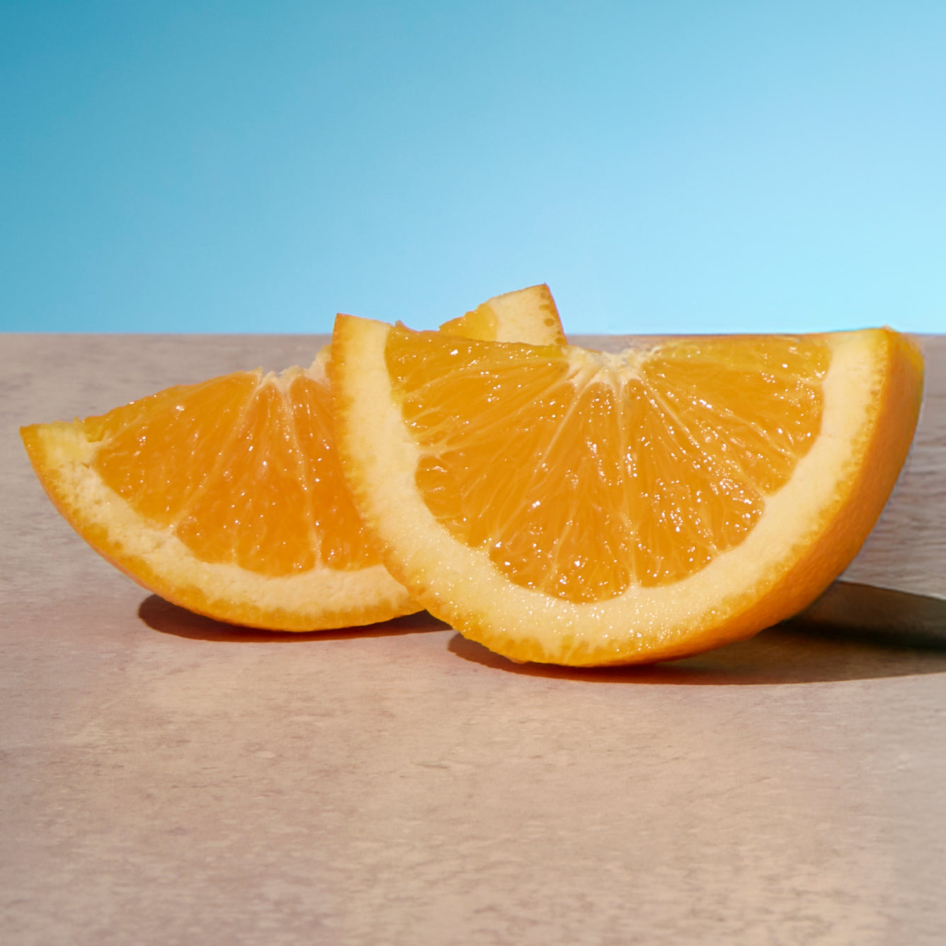 Two orange slices on a wooden surface with a blue background