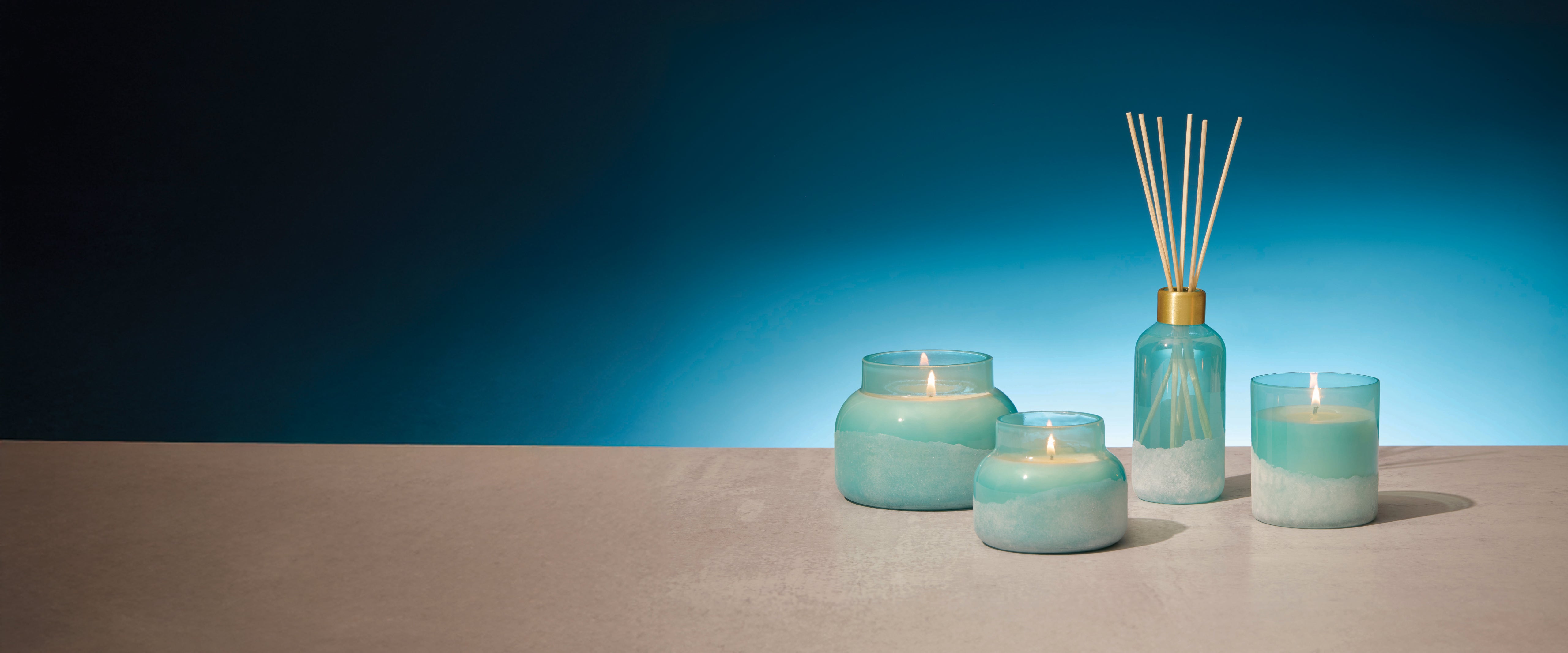 Set of teal candles and diffuser against a blue background