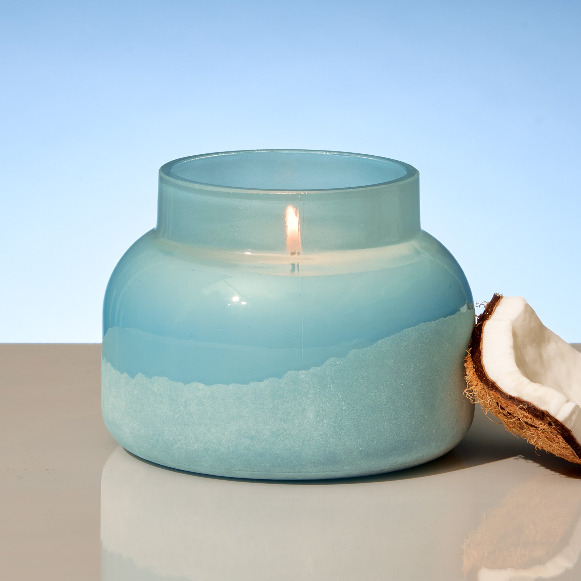 Candle in a blue glass jar with a light blue background