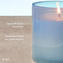 Blue candle with text indicating burn time, texture, and size on a wooden surface