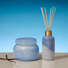 Blue candle and diffuser with vanilla fragrance against a clear blue sky