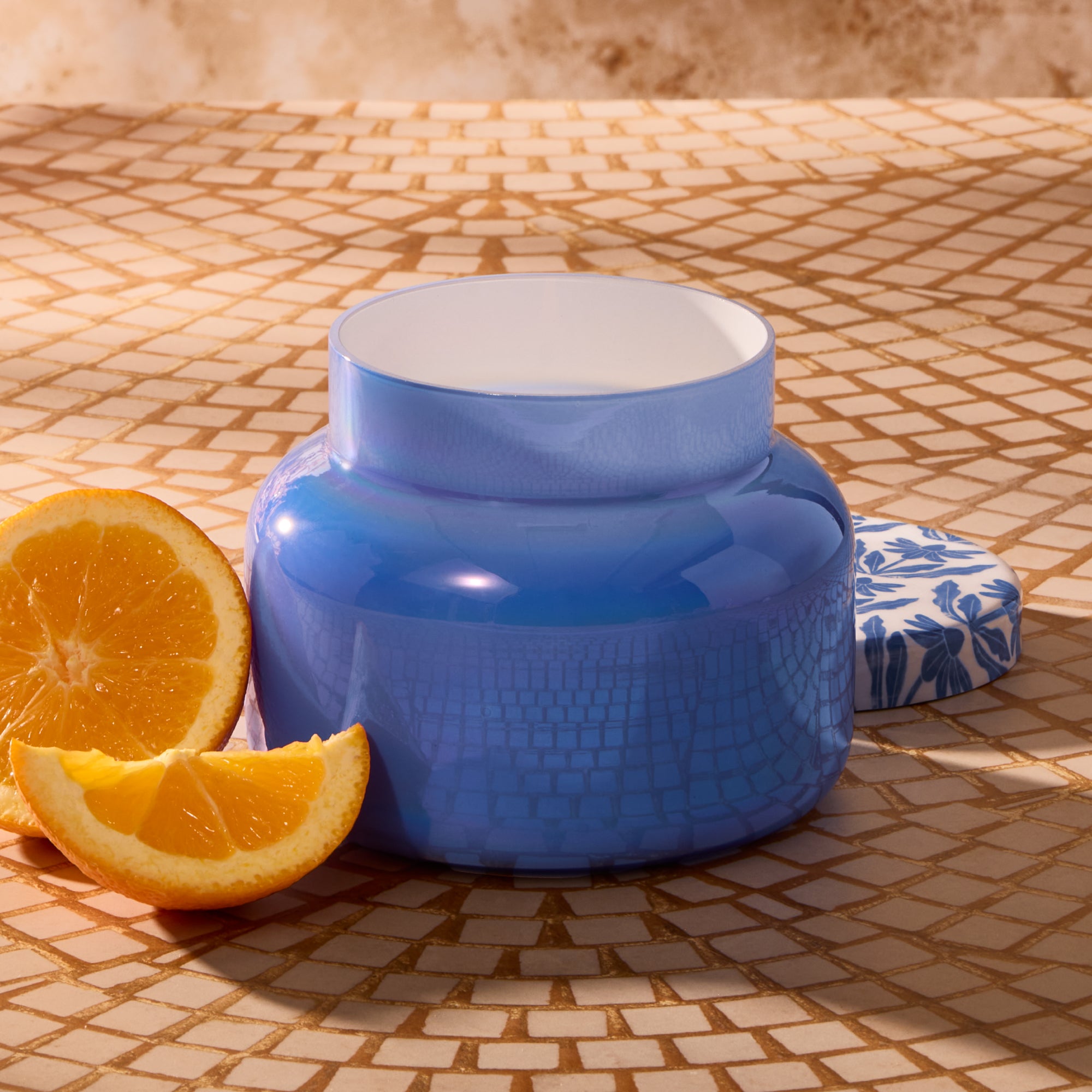 Blue ceramic container on a tiled surface with oranges nearby
