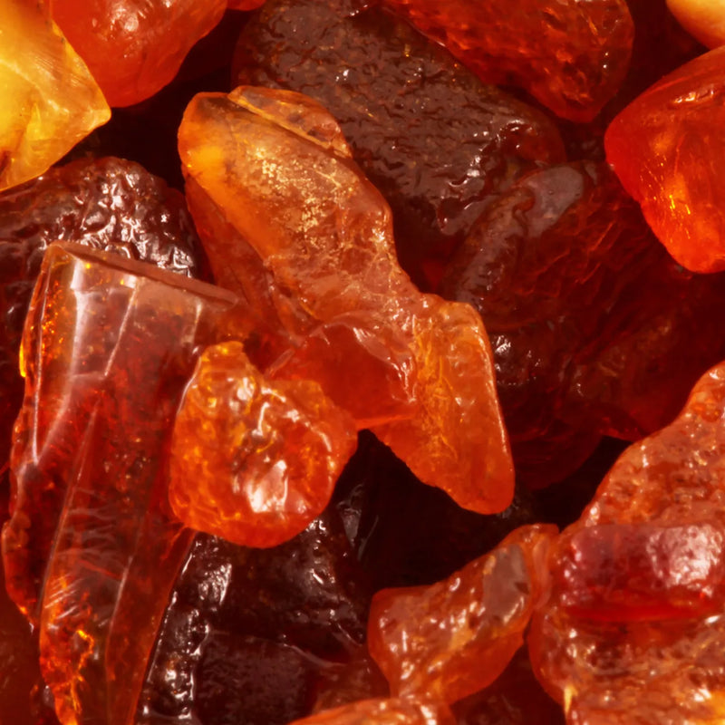 Close-up of translucent amber-orange and deep reddish-brown gemstone-like pieces filling the frame.