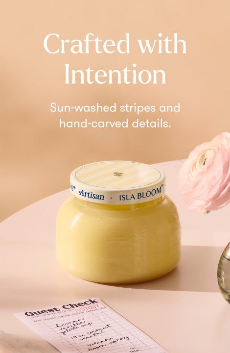 Yellow candle with a white label on a pink surface, text 'Crafted with Intention' above.