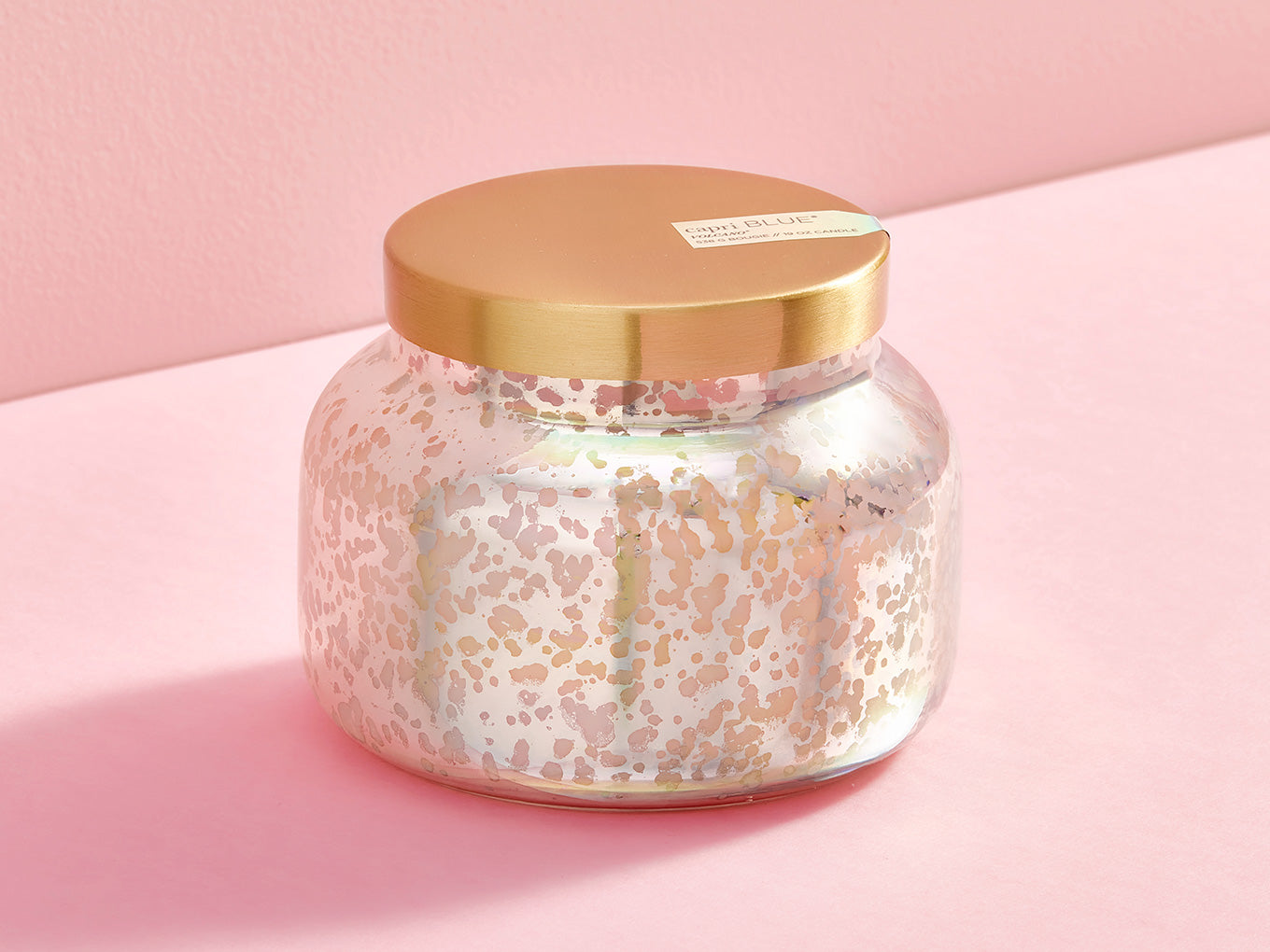 Glass jar with gold lid on a pink background