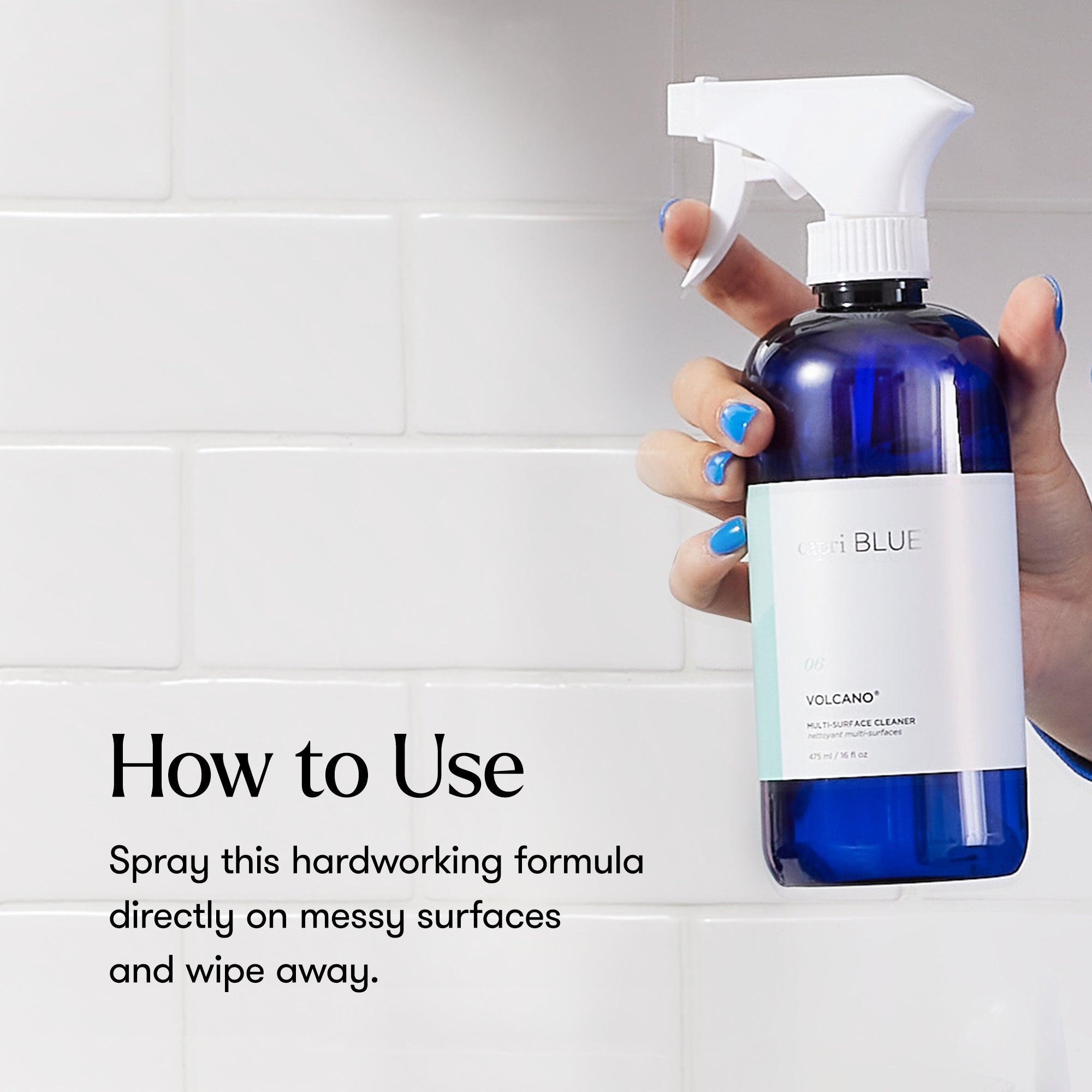 Hand holding a blue spray bottle with a white label against a tiled wall background.