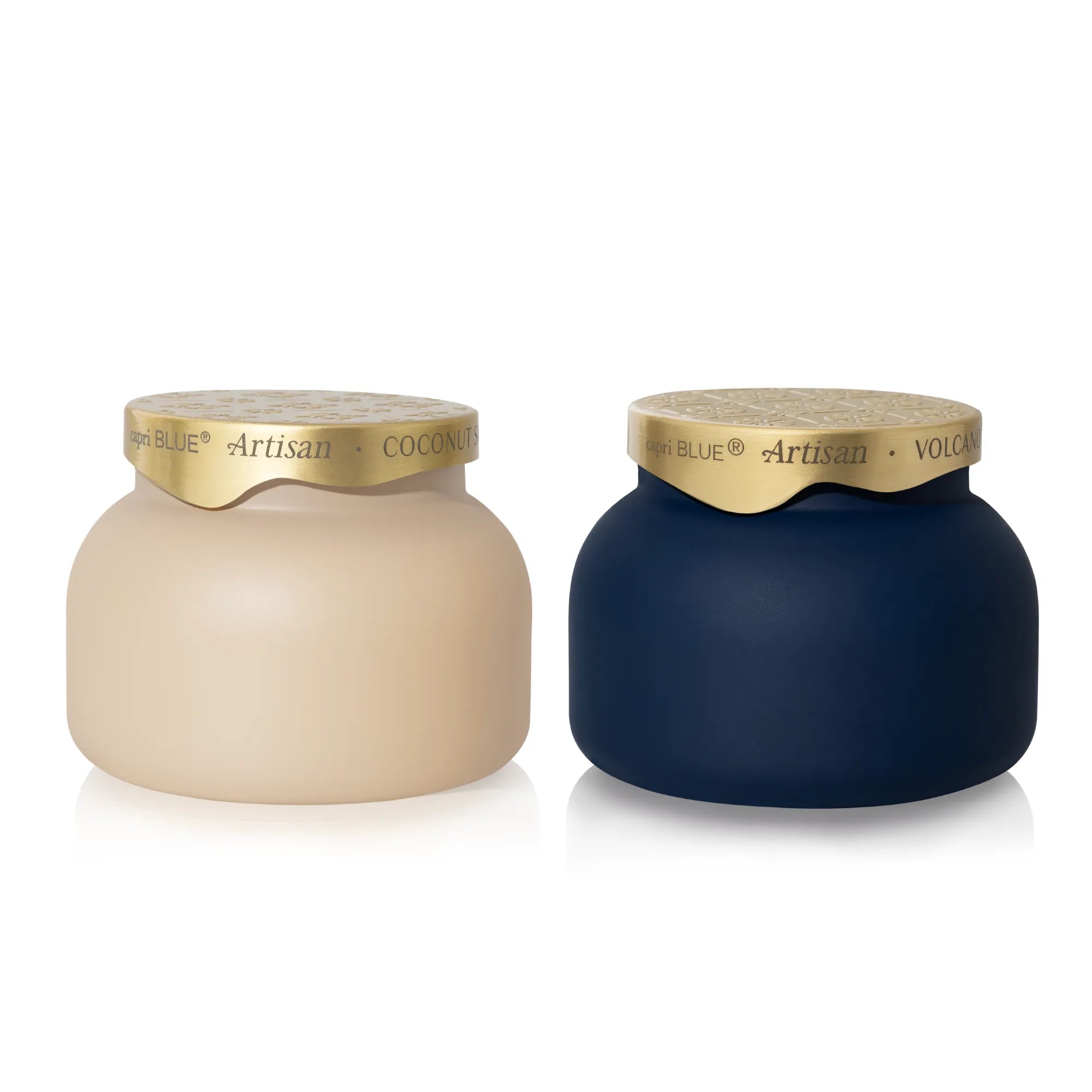 Two matte-finish decorative jars on a white background, one in warm beige labeled Coconut and one in deep navy labeled Volcano. Both have metallic gold lids with the brand name visible.
