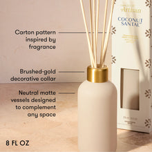 A reed diffuser bottle in a matte cream color with a brushed gold collar and natural reeds, shown next to its branded Coconut Santal box. The image includes text callouts describing the product features.