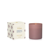 A matte dusty rose glass candle next to its cream-colored packaging box with purple floral patterns. The box is labeled 'Artisan Havana Vanilla' and features a small gold logo at the top.