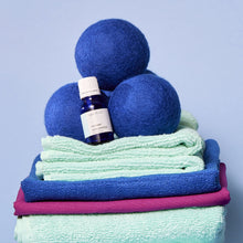 Volcano Laundry Fragrance Oil on a stack of laundry with dryer balls