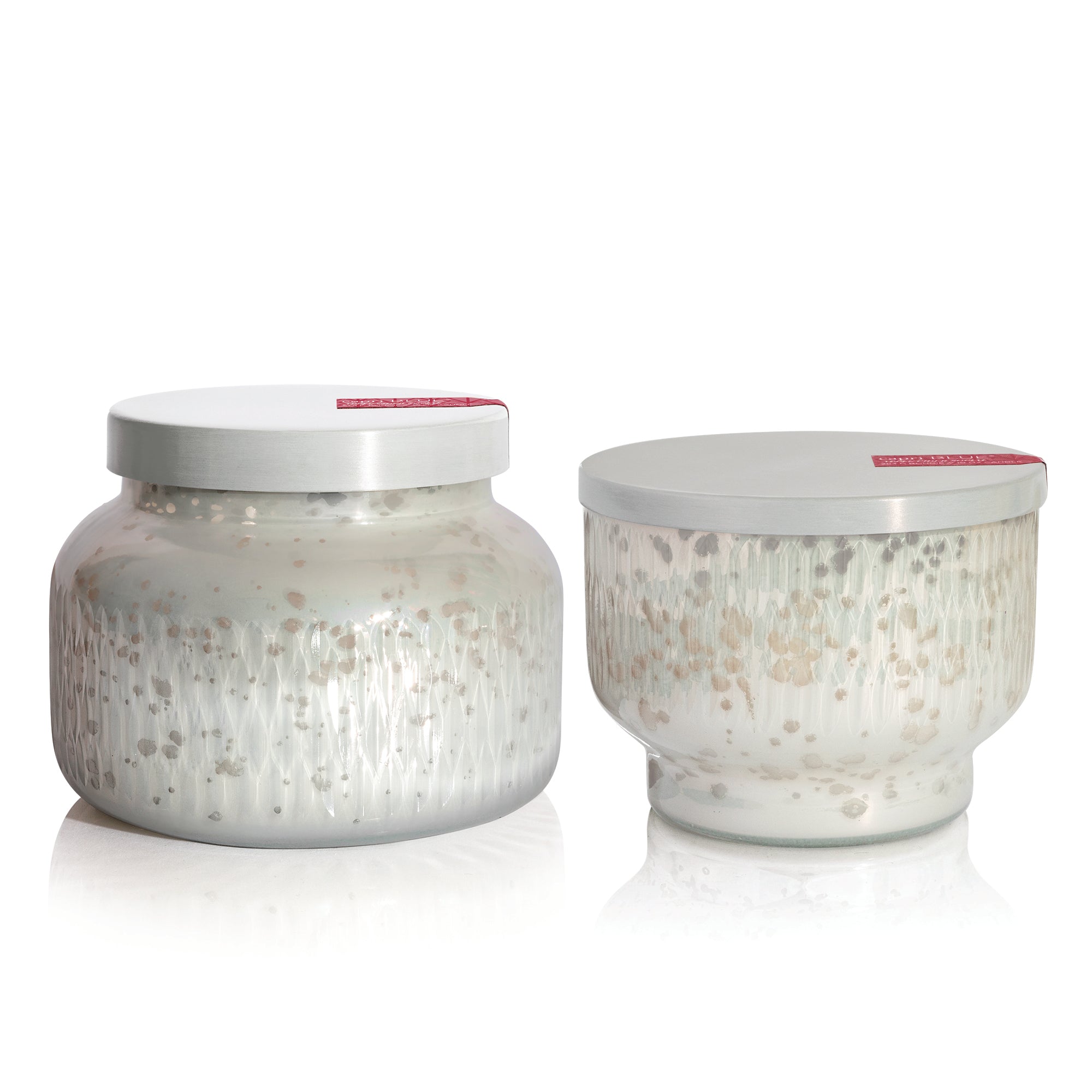 Two glass scented candle jars with decorative lids on a white background