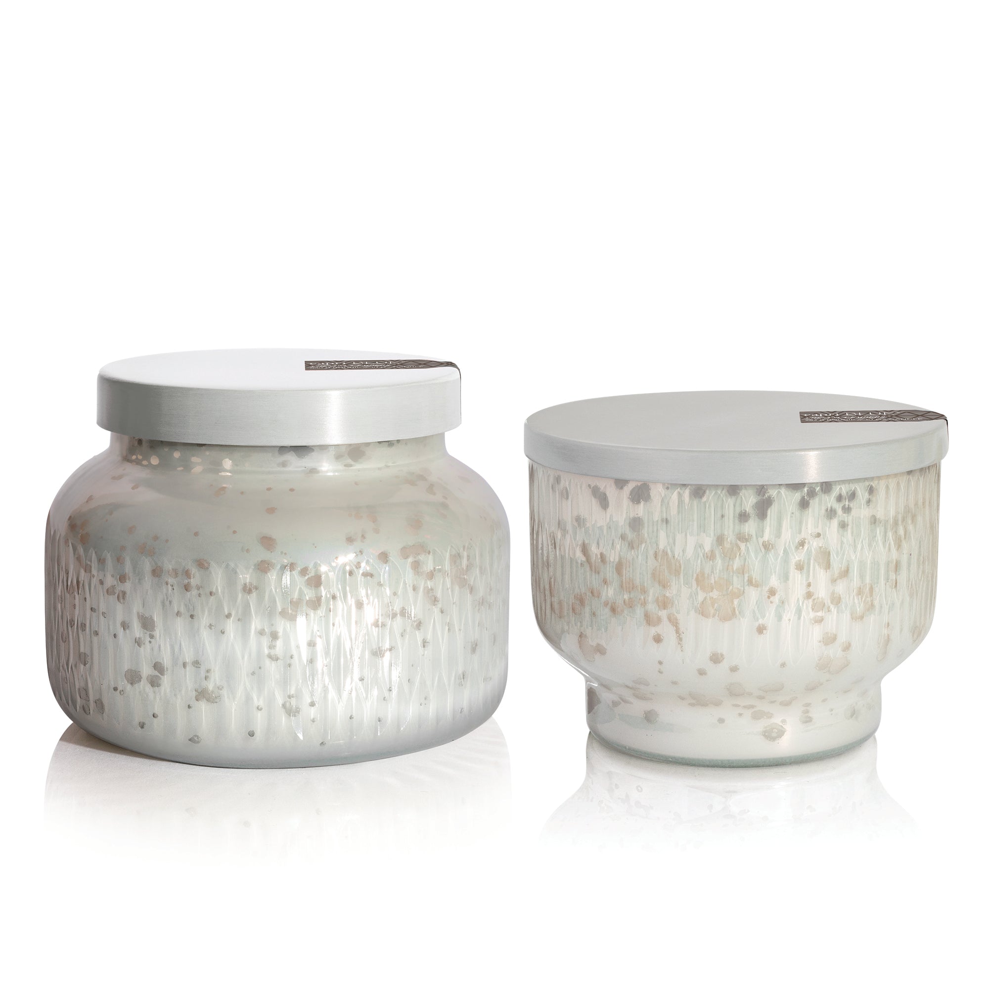 Two glass scented candle jars with silver lids on a white background