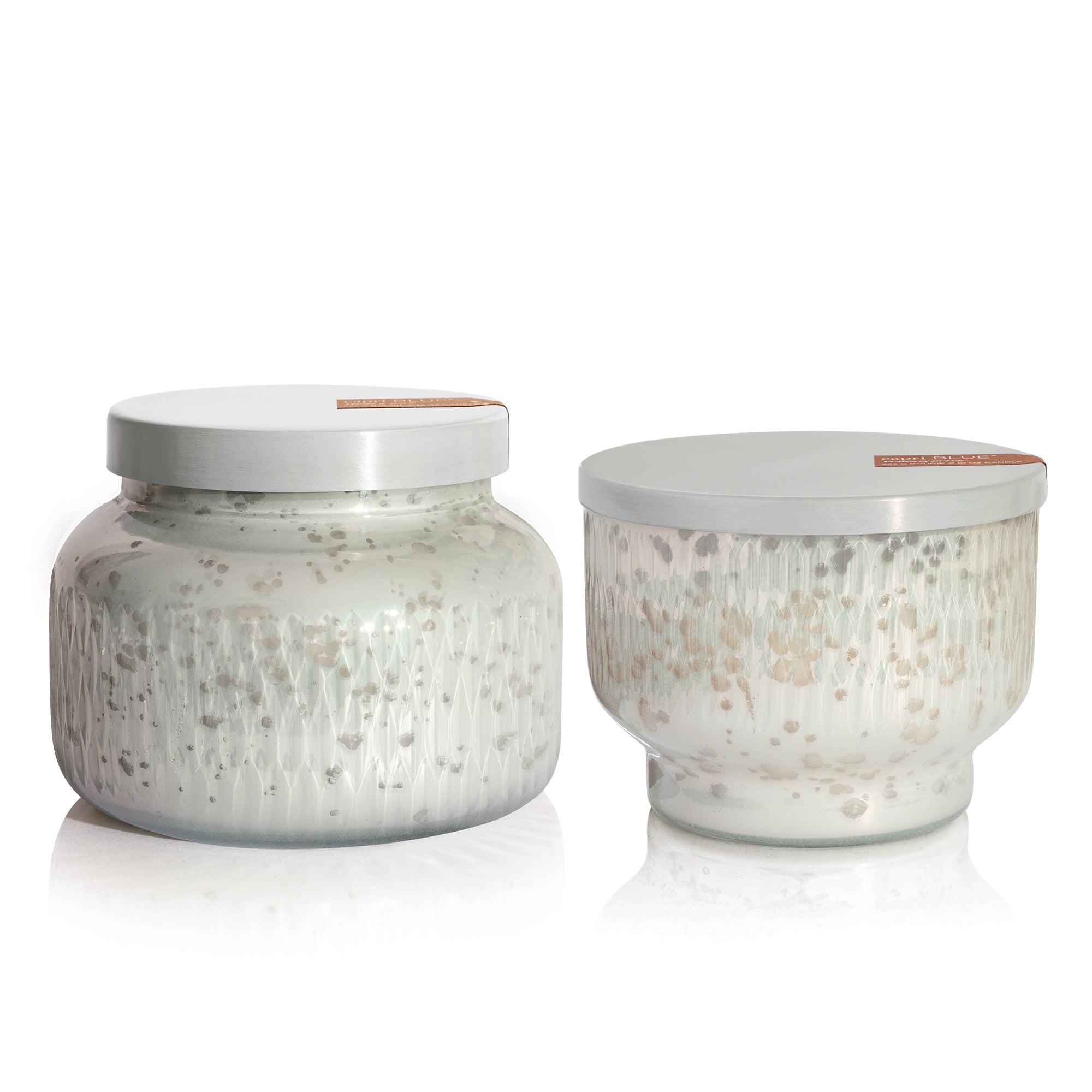 Two glass scented candle jars with speckled patterns and white lids on a white background