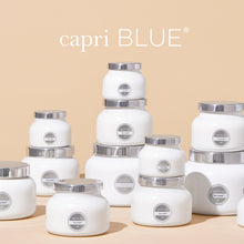 White candles with silver lids on a beige background, featuring the 'capri BLUE' brand.