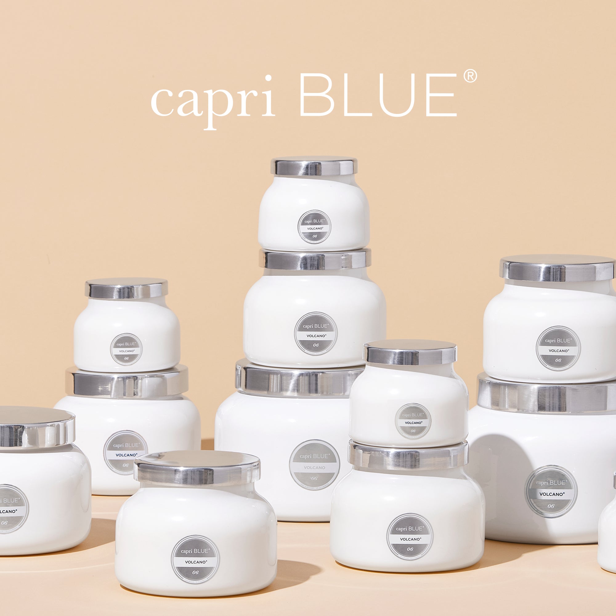 White candles with silver lids on a beige background, featuring the 'capri BLUE' brand.