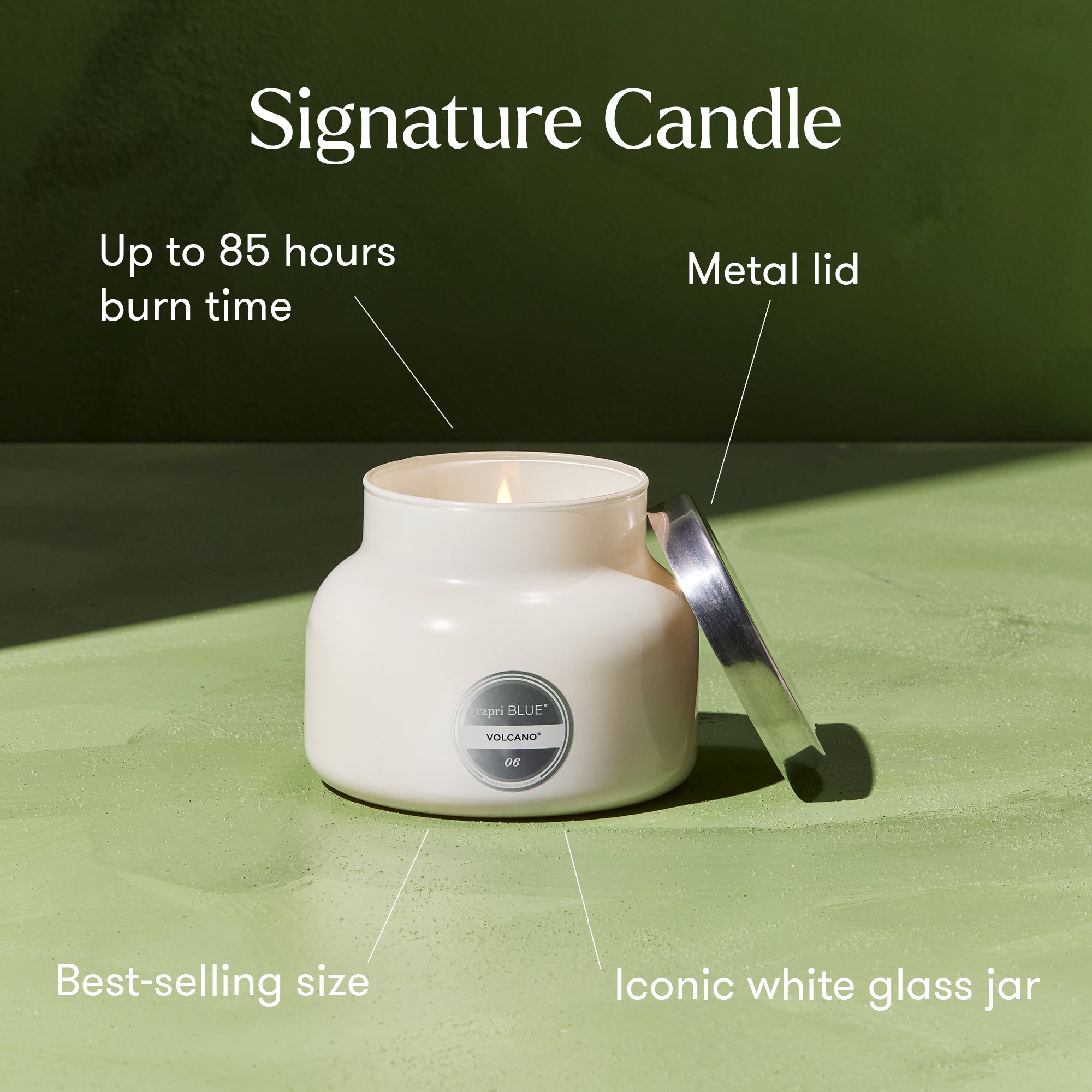 White candle in a glass jar with metal lid on a green surface, labeled with features.