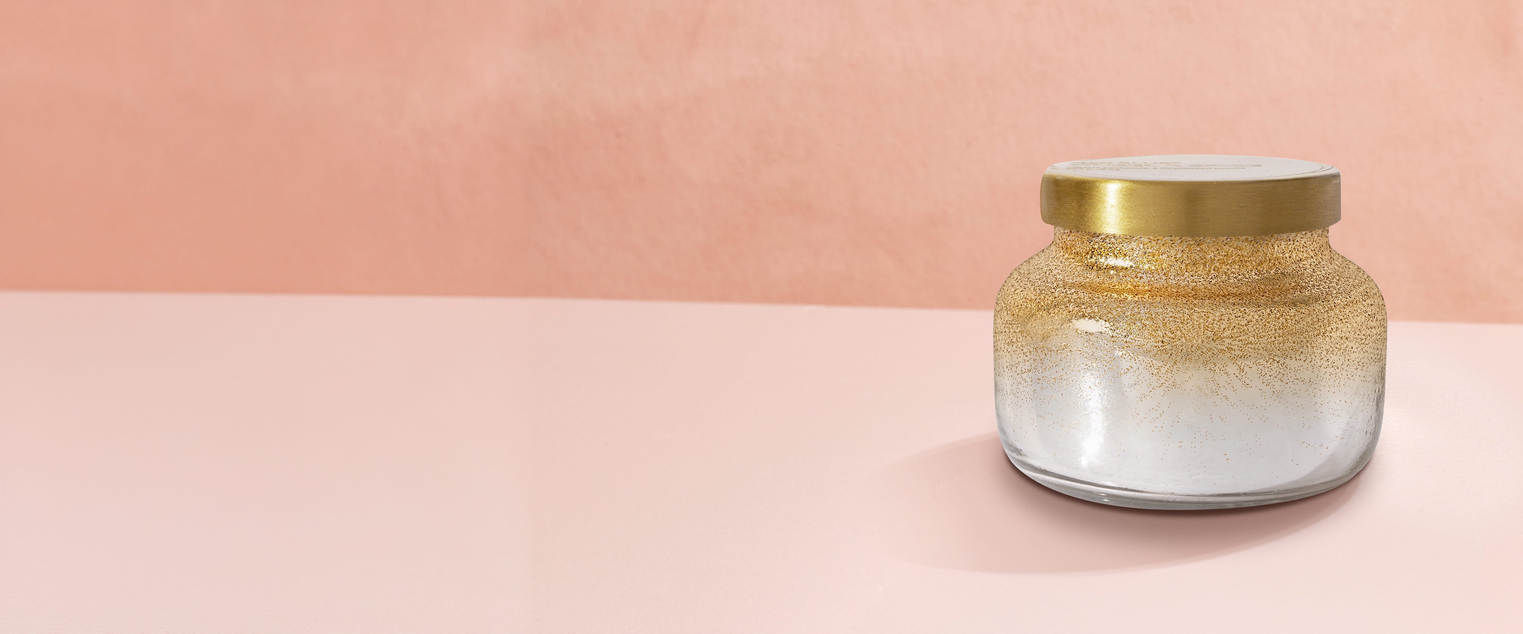 Candle with a gold lid on a pink background