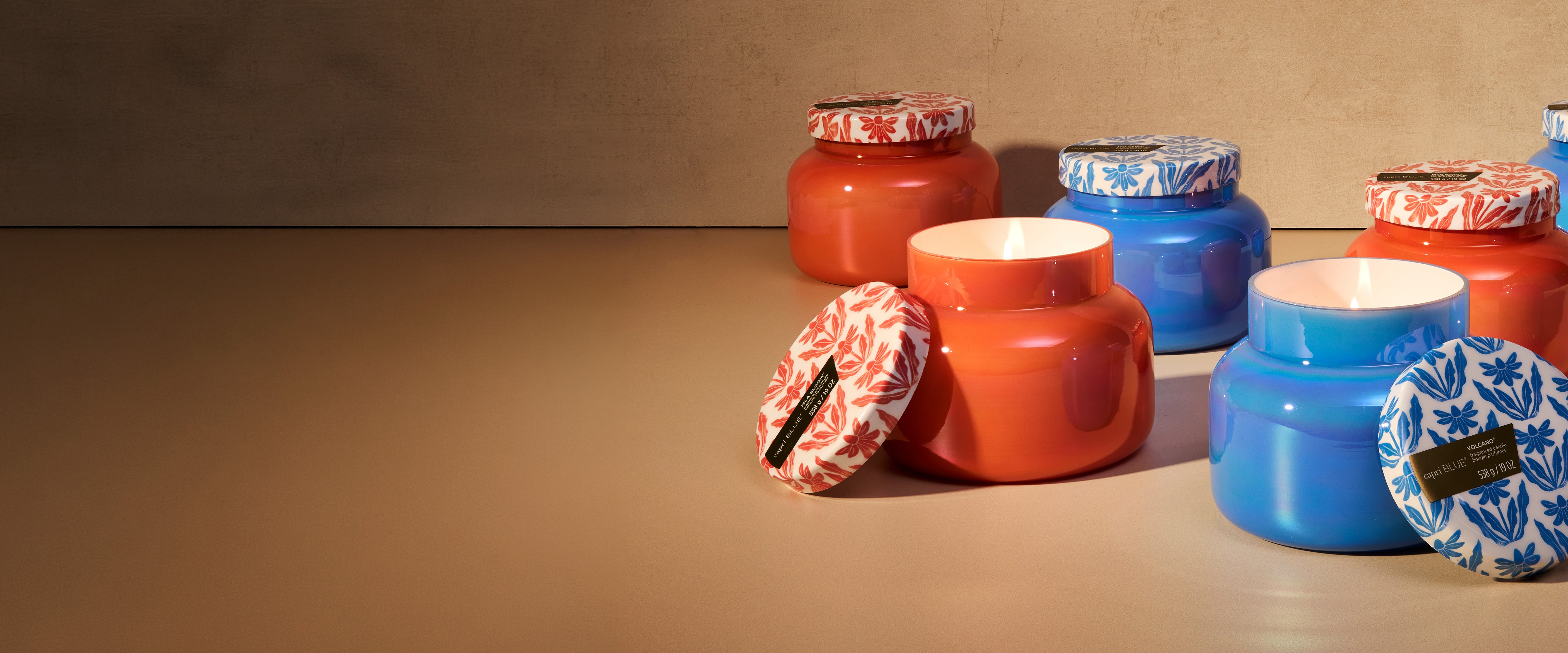 Colorful jars with decorative lids on a brown surface