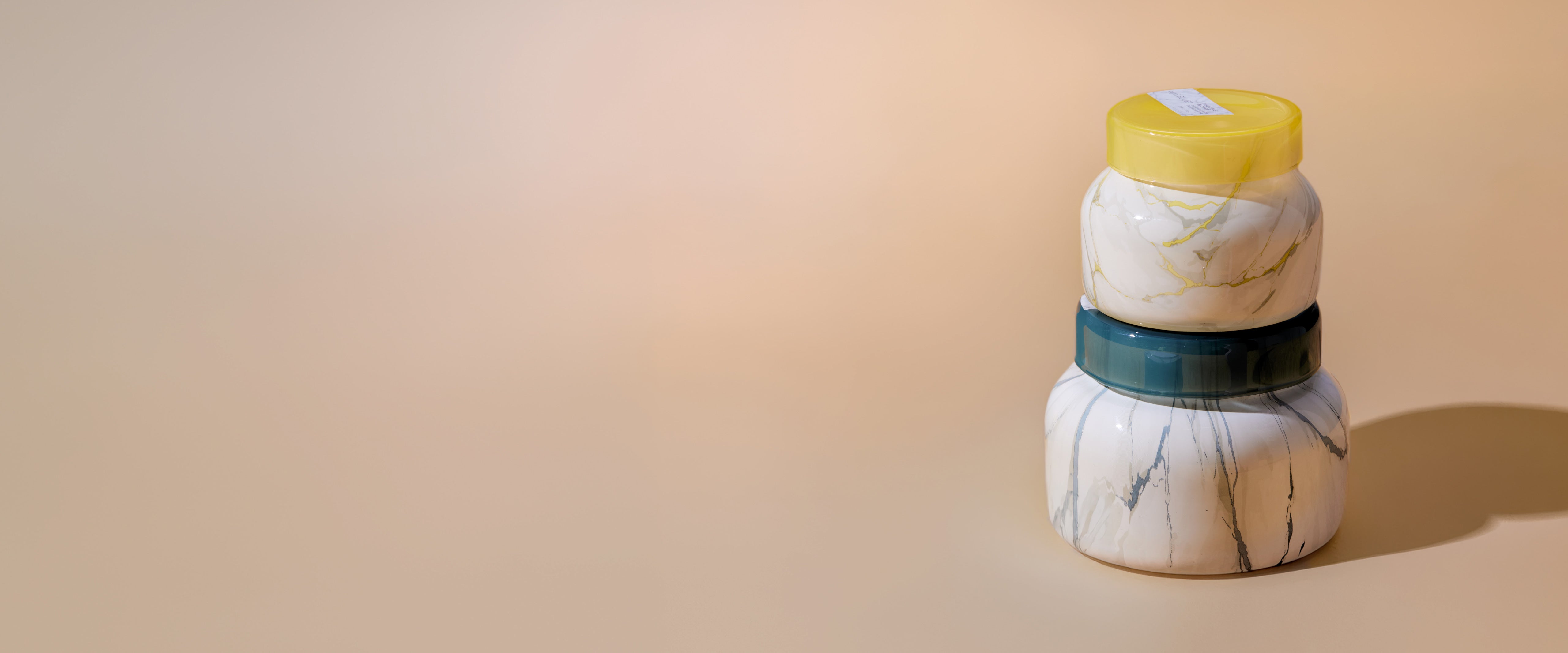 Two candles stacked on top of each other on a tan background
