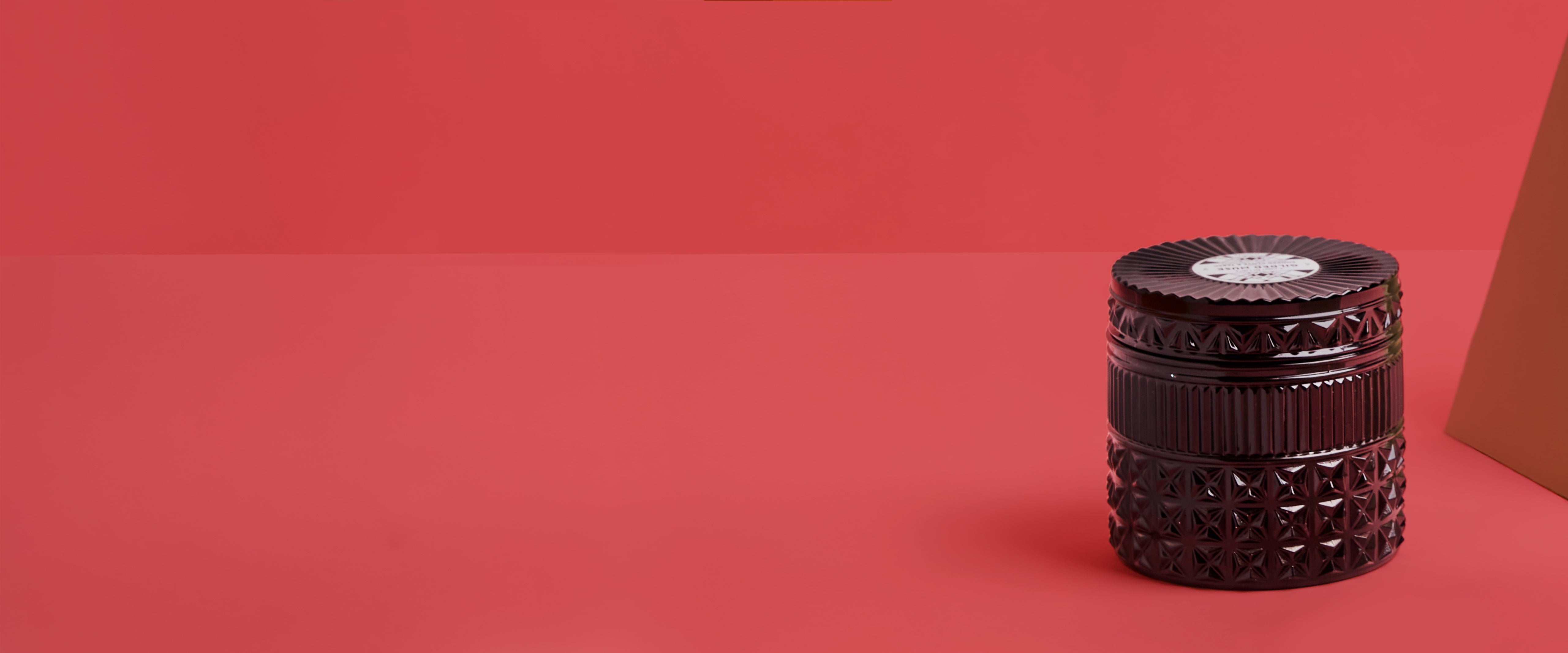 Smoked Clove & Tabac black gilded candle on a red background