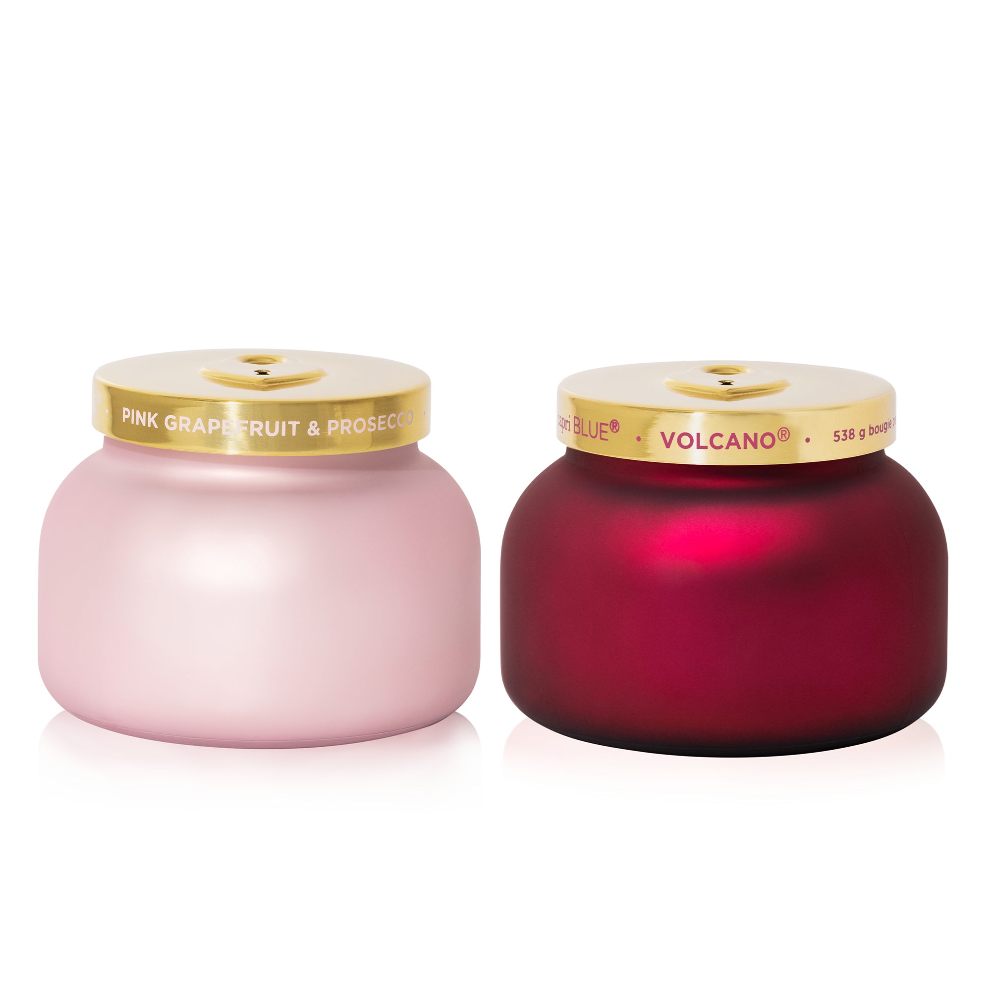 Two candles, one pink and one red, with gold lids on a white background.